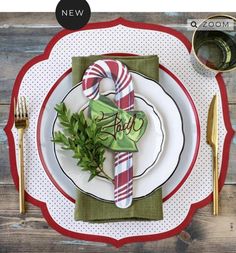 a place setting on a wooden table with napkins, silverware and greenery