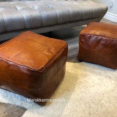 two brown leather ottomans sitting on top of a white rug