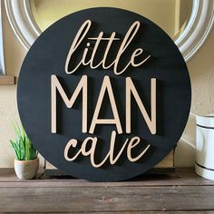 a wooden sign that says little man cave on the side of a shelf next to a potted plant