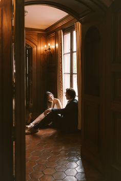 a woman sitting on the floor in front of a window