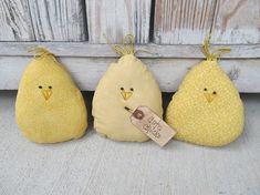 three stuffed birds are hanging from the side of a wooden wall with a tag on it