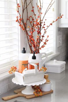 a kitchen counter with white dishes and orange flowers in the vase on top of it