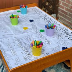 the table is decorated with markers and pencils in buckets on top of it