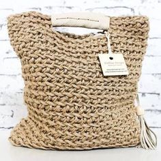 a crocheted bag with a tag hanging from the handle on it's side