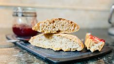 two pieces of bread sitting on top of a cutting board with jam in the background