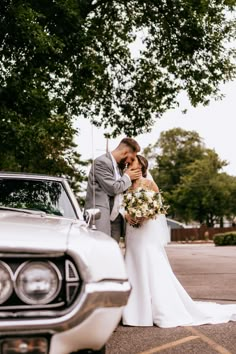 a bride and groom standing in front of an old car