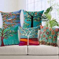 four colorful pillows on a white couch in front of a plant and potted tree