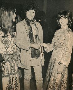 an old black and white photo of two women shaking hands with a man in a suit