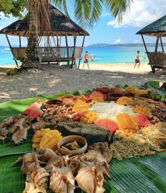 food is laid out on a banana leaf at the beach