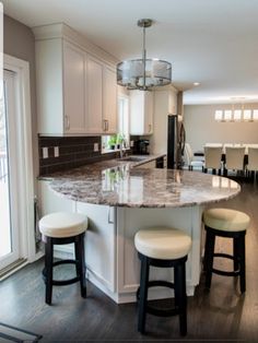 a kitchen with two stools next to an island in the middle of the room