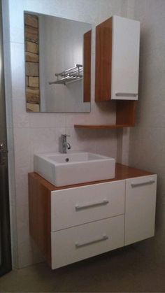 a white sink sitting under a bathroom mirror next to a wooden cabinet and counter top