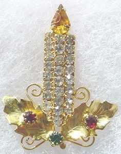 a golden brooch with leaves and crystals on it's side, sitting on a white surface