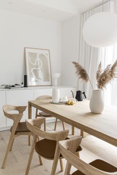 a wooden table with two vases on top of it next to a white wall