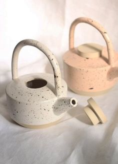 two ceramic teapots with handles on a white background