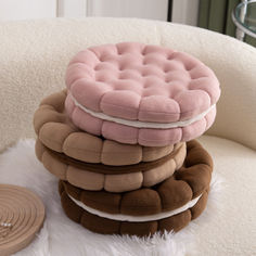 a stack of pillows sitting on top of a white chair next to a round object