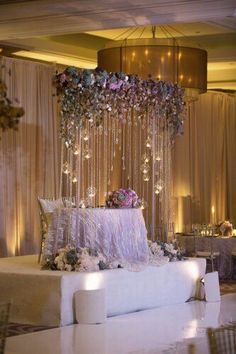 a white couch sitting under a chandelier filled with flowers and candles on top of a table