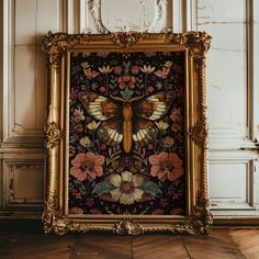 an ornate gold frame with a painting of a moth on it in front of a white wall