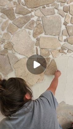 a girl is painting a stone wall with white paint