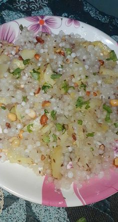 a plate with rice and nuts on it sitting on a floral tablecloth covered table