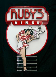 a sign that says ruby's diner with a woman holding a hot dog in her hand