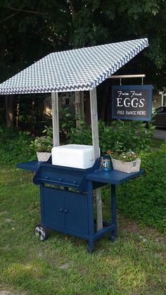 an outdoor bbq is set up in the grass with a checkered cover over it