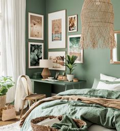 a bedroom with green walls and pictures on the wall above the bed, along with wicker baskets