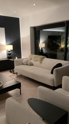 a living room with white couches and black tables