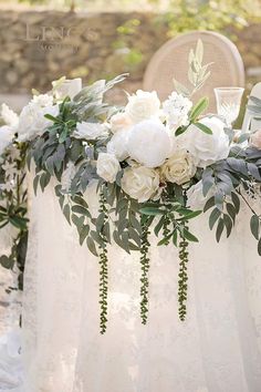 the table is set with white flowers and greenery