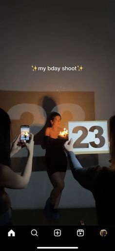 two women holding up cell phones in front of a screen with the number twenty three on it