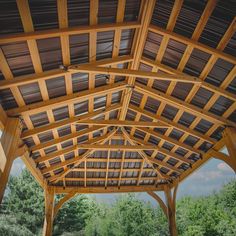 the inside of a wooden gazebo with trees in the background