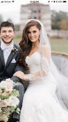 a bride and groom sitting on a bench in front of the camera, posing for a photo