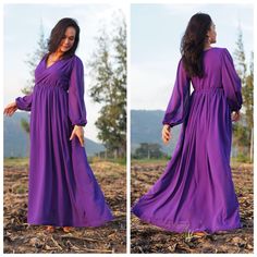 a woman in a long purple dress is standing on the ground with her hands behind her back