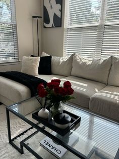 a living room with a couch, coffee table and flowers in the vase on top