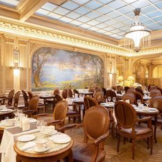 a dining room with tables and chairs in front of a large painting on the wall