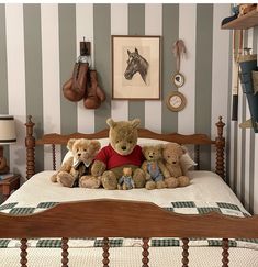 three teddy bears sitting on top of a bed in a room with striped wallpaper