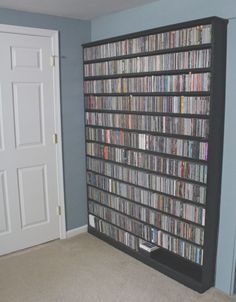 a room with a large book shelf filled with dvd's and video game equipment