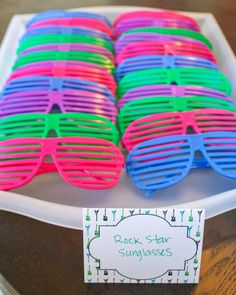 colorful sunglasses are sitting on a tray with a sign that says rock star sunggles