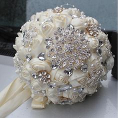 the bridal bouquet is adorned with crystal stones and pearls, along with ivory roses