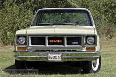 an old gmc truck is parked in the grass