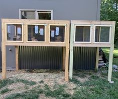 a house made out of metal and wood with windows on each side, in the grass