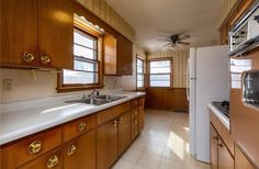 an empty kitchen with wood cabinets and white counter tops is seen in this image from the doorway