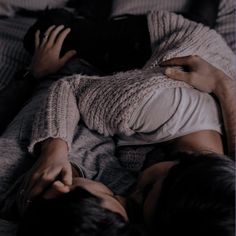 a man and woman laying on top of a bed next to each other in the dark