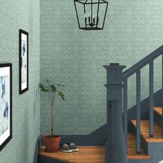 a room with some stairs and a light hanging from the ceiling above it, next to a potted plant