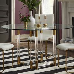 a glass dining table with two chairs and a potted plant on the top, in front of a fireplace