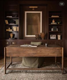 a wooden desk sitting on top of a rug in front of a bookshelf