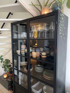 a black china cabinet with glass doors and dishes on it