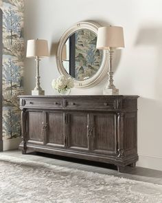 a large mirror on top of a dresser next to two lamps and a lamp shade