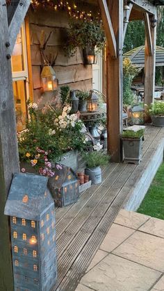 an outdoor area with potted plants and lights on the side of the house in the evening