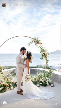 a bride and groom standing under an arch with flowers