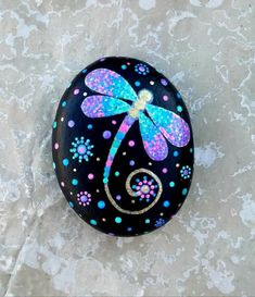 a painted rock with a dragonfly on it